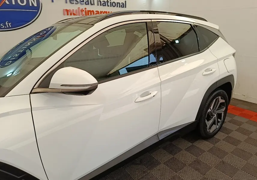 Vue côté gauche du Hyundai Tucson blanc 2022, mettant en valeur les lignes anguleuses et les jantes modernes.