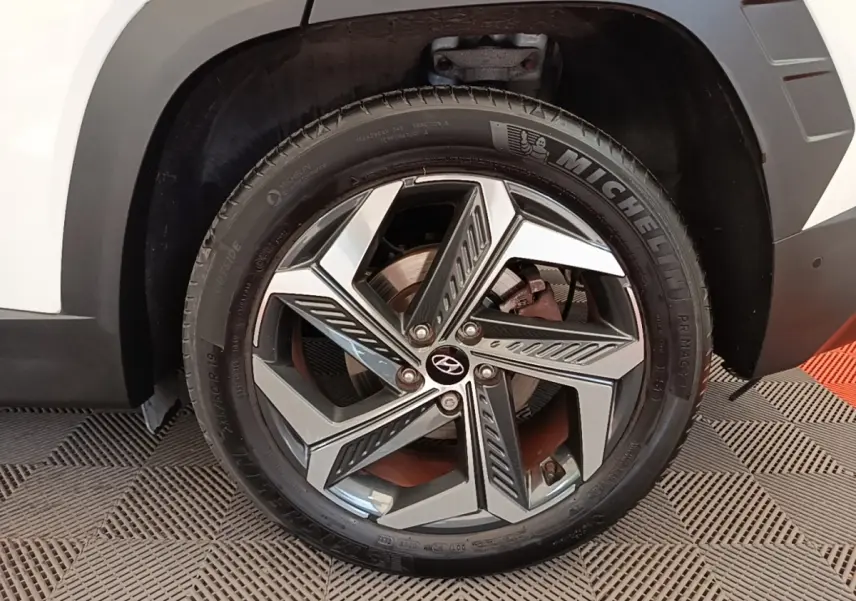Gros plan sur la roue avant droite blanche du Hyundai Tucson 1.6 Hybrid 230 Executive avec jante alliage moderne.