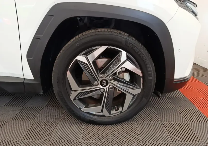 Gros plan sur la roue avant droite d’un Hyundai Tucson blanc 2022 avec jante alliage au design moderne.