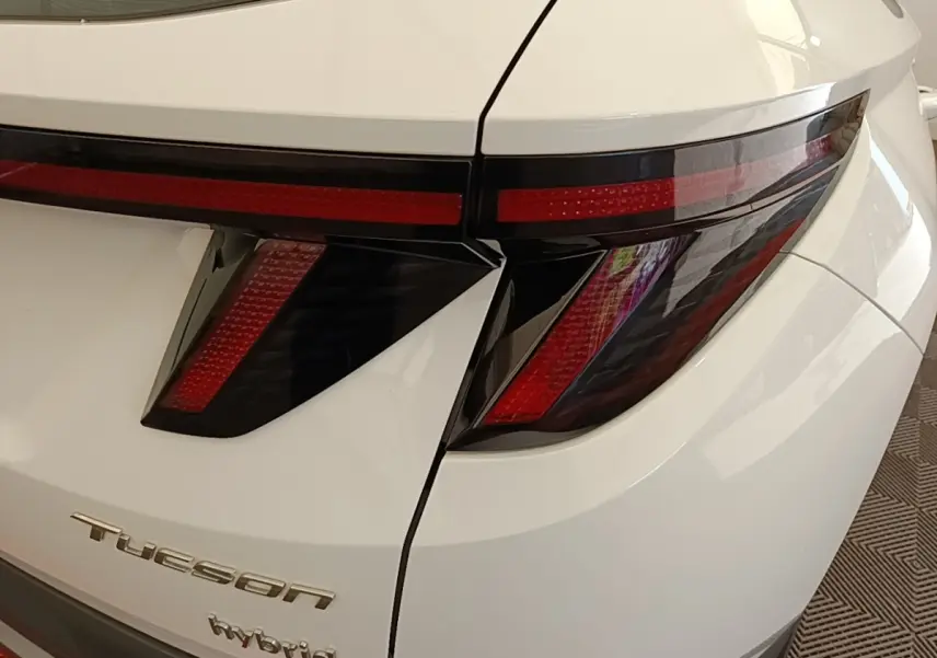 Gros plan sur l’arrière droit blanc d’un Hyundai Tucson Hybrid 2022, mettant en valeur ses feux arrière LED au design anguleux.