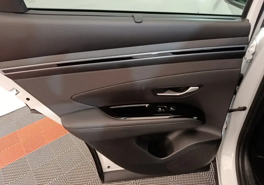 Vue intérieure de la porte avant droite du Hyundai Tucson blanc 2022, avec garniture noire et commandes électriques.