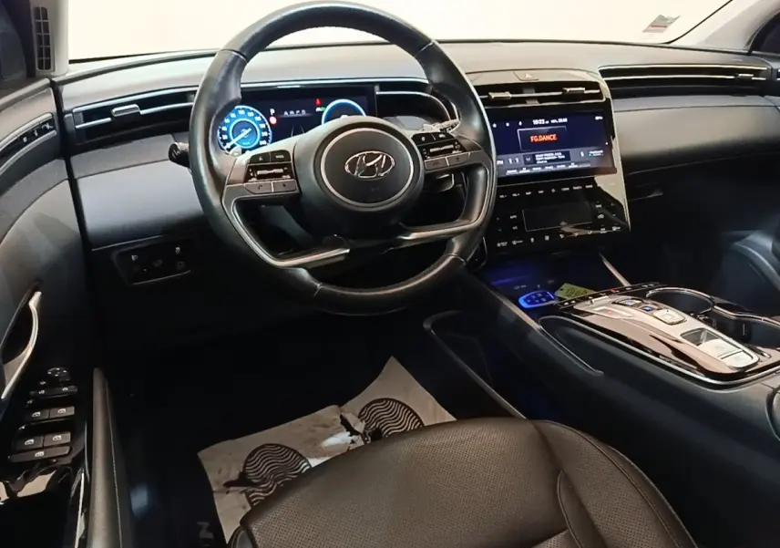 Intérieur du Hyundai Tucson 1.6 Hybrid 230 Executive 2022, vue du poste de conduite avec volant cuir et écran tactile central.