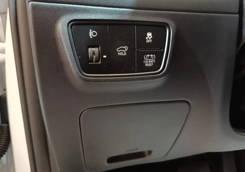 Vue rapprochée des commandes noires sur tableau de bord côté gauche du Hyundai Tucson blanc 1.6 Hybrid 230 Executive 2022.