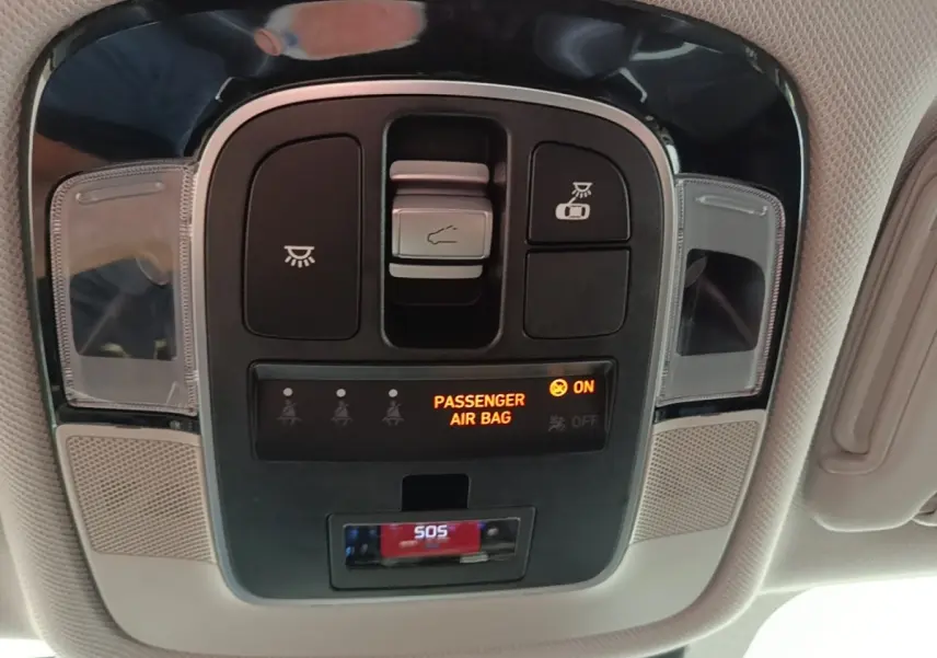Vue en contre-plongée du panneau de commandes au plafond du Hyundai Tucson blanc, avec indicateur airbag passager et bouton SOS.