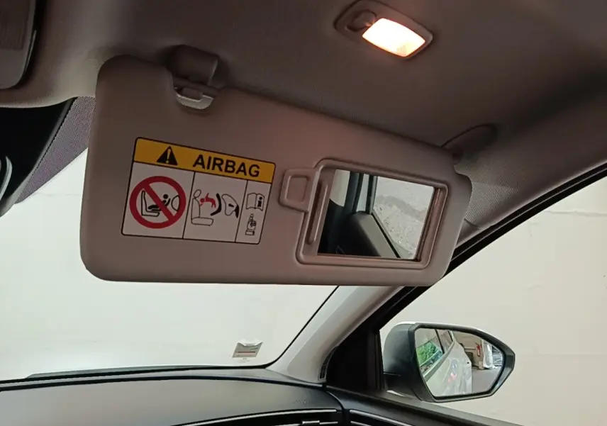 Détail intérieur du pare-soleil côté conducteur avec miroir et avertissement airbag dans un Hyundai Tucson blanc 2022.