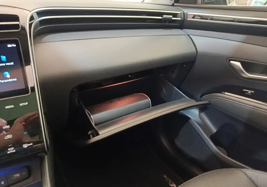 Vue intérieure côté passager du tableau de bord noir avec boîte à gants ouverte du Hyundai Tucson blanc 2022 hybride.
