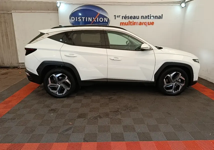 Vue de profil côté gauche d'un Hyundai Tucson blanc 2022 hybride, avec jantes alliage et toit ouvrant électrique.
