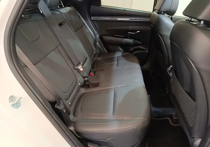 Vue intérieure côté arrière gauche du Hyundai Tucson 1.6 Hybrid 230 Executive 2022, sièges en cuir noir et portière blanche ouverte.