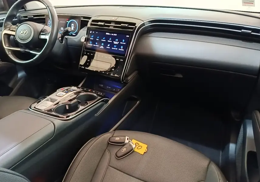 Intérieur noir du Hyundai Tucson 1.6 Hybrid 2022 vu côté passager, avec tableau de bord et clés sur siège avant.