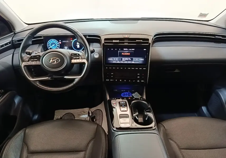 Vue intérieure avant du Hyundai Tucson 1.6 Hybrid 230 Executive 2022, tableau de bord noir avec écran tactile central et volant multifonctions.