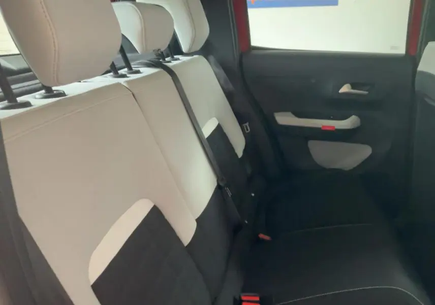 Vue intérieure côté droit des sièges arrière bicolores beige et noir de la Citroën C3 ë-113 Berline Max 2025 rouge métal foncé.