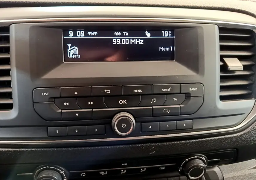 Vue rapprochée du tableau de bord noir du Toyota Proace Verso 2019 avec écran radio affichant 99.00 MHz.