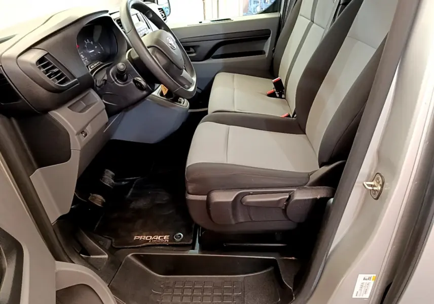 Vue intérieure côté conducteur du Toyota Proace Verso 2019 gris clair, montrant les sièges avant et le volant multifonctions.