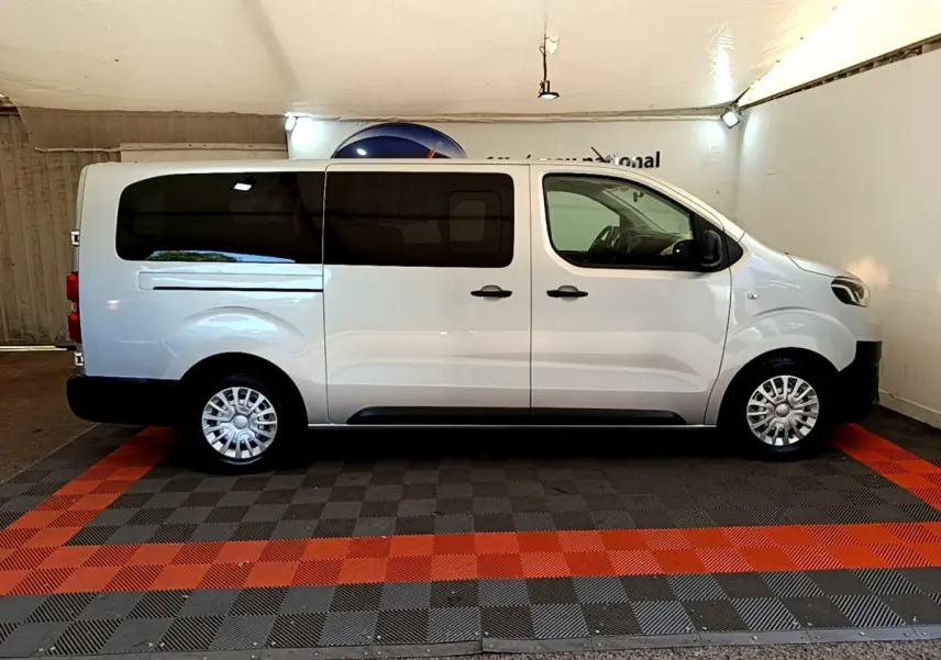 Profil côté droit d'un Toyota Proace Verso gris clair 2019 avec vitres arrière teintées et jantes acier en intérieur fermé.
