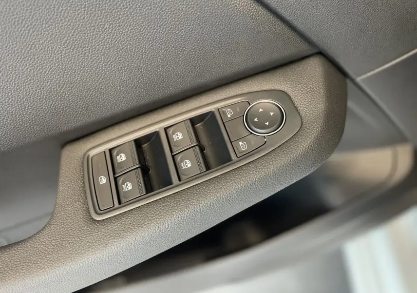 Gros plan sur les commandes de lève-vitres et rétroviseurs côté conducteur de la Renault Clio blanche 2025.