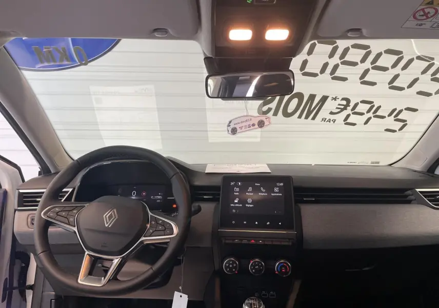 Vue intérieure avant de la Renault Clio 2025, tableau de bord noir avec écran tactile et volant multifonction.