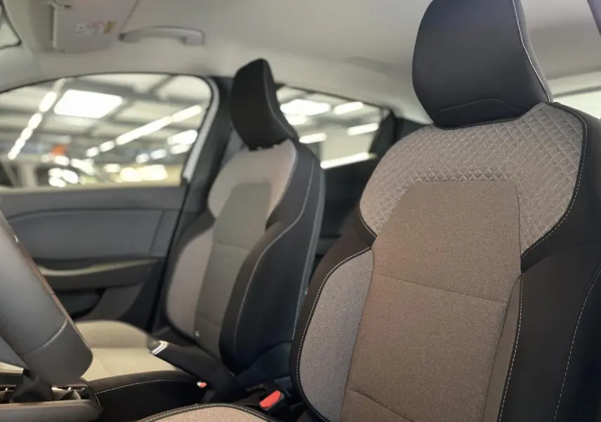 Gros plan sur les sièges avant gris et noirs de la Renault Clio 1.5 Blue dCi 2025 dans un intérieur moderne.
