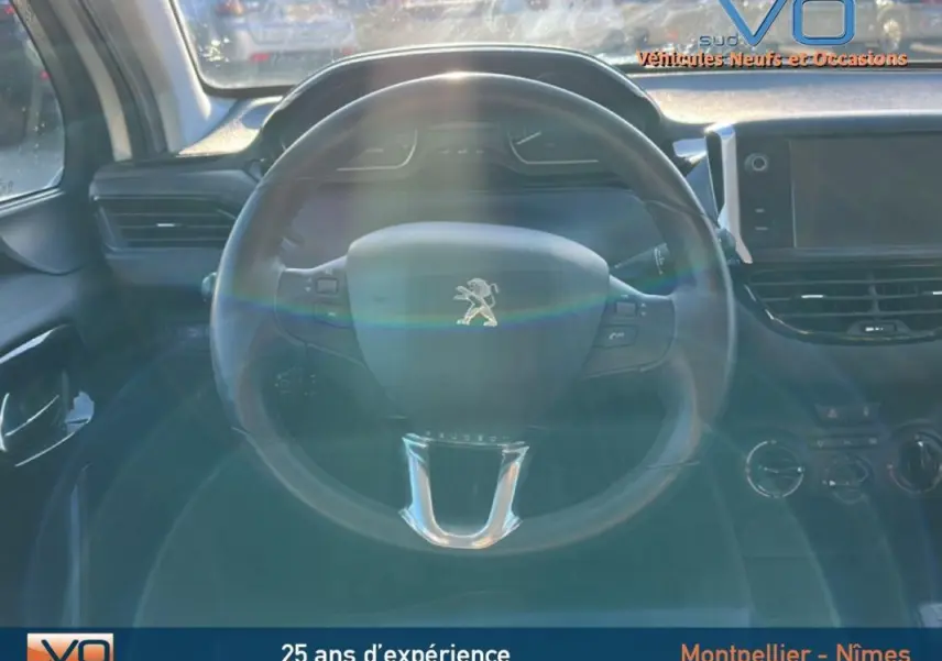 Intérieur de la Peugeot 208 blanc 2015, vue centrée sur le volant avec tableau de bord et écran tactile visibles.