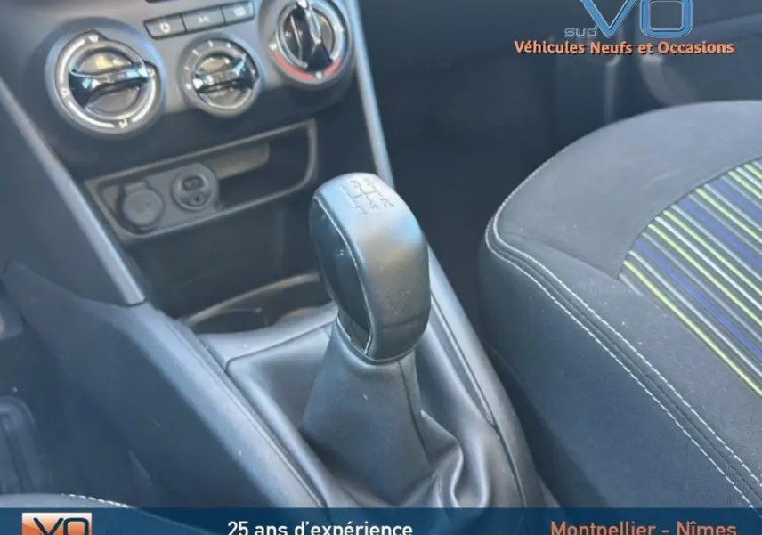 Gros plan sur le levier de vitesses manuel et la console centrale du Peugeot 208 blanc, avec siège avant tissu rayé visible.