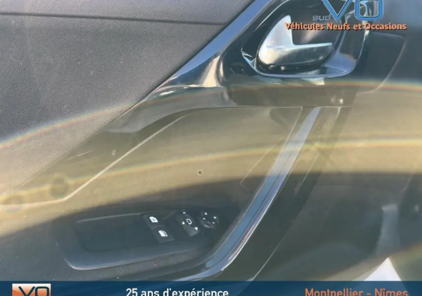 Détail de la porte avant gauche noire de la Peugeot 208 Urban Soul avec commandes électriques et poignée chromée.