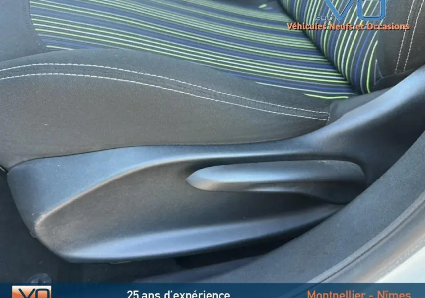 Gros plan sur le siège conducteur à réglage manuel de la Peugeot 208 blanc, tissu rayé vert et bleu visible.