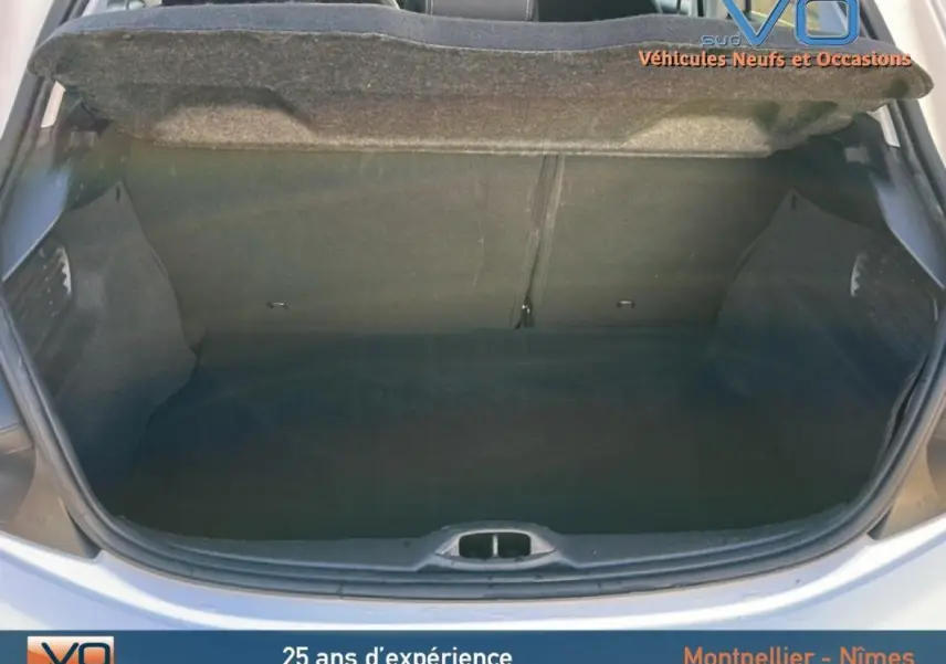 Coffre ouvert d'une Peugeot 208 blanche vue de l'arrière, montrant l'espace de chargement vide et la plage arrière relevée.