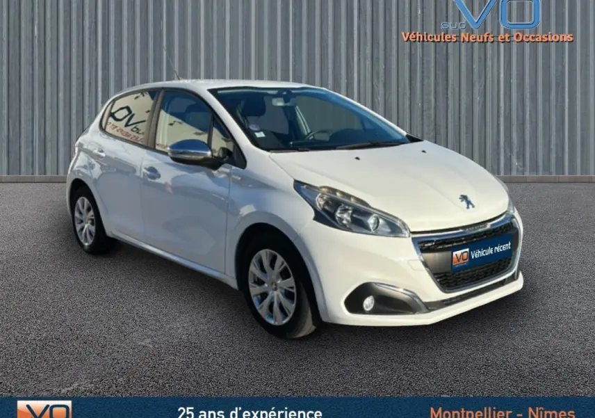 Peugeot 208 blanc vue 3/4 avant droit, jantes 15 pouces classiques, phares et antibrouillards visibles, arrière légèrement masqué.
