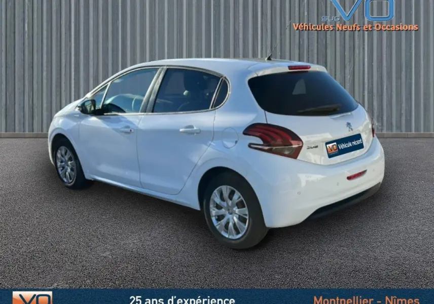 Vue 3/4 arrière droite d'une Peugeot 208 blanche de 2015 avec jantes classiques 15 pouces et vitres teintées arrière.