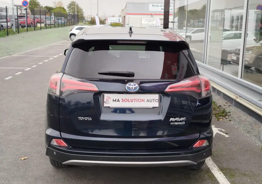 Vue arrière d'un Toyota RAV4 noir cobalt hybride 2017, avec feux LED et logo visible sur un parking urbain.