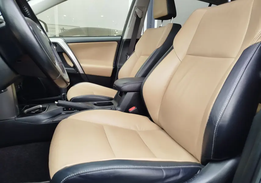 Intérieur beige et noir du Toyota RAV4 2017, vue rapprochée des sièges avant côté conducteur.