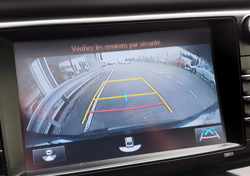 Vue de la caméra de recul du Toyota RAV4 noir cobalt, affichant les lignes de guidage sur un parking urbain.