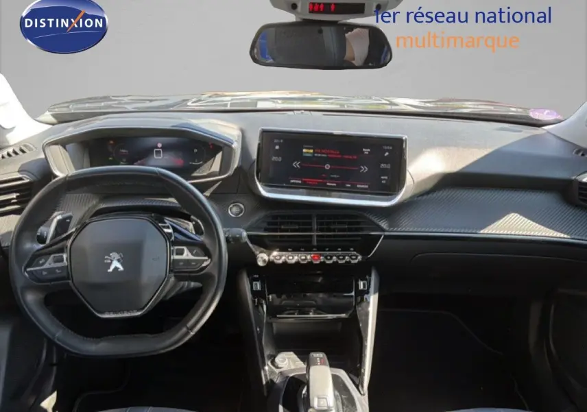 Vue intérieure avant du tableau de bord et volant noir d'une Peugeot 2008 gris platinium, avec écran tactile central et commandes modernes.