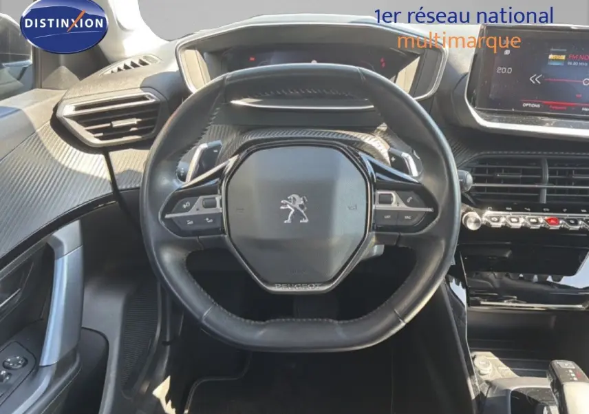 Vue intérieure centrée sur le volant noir du Peugeot 2008 2020, avec tableau de bord et écran tactile en arrière-plan.