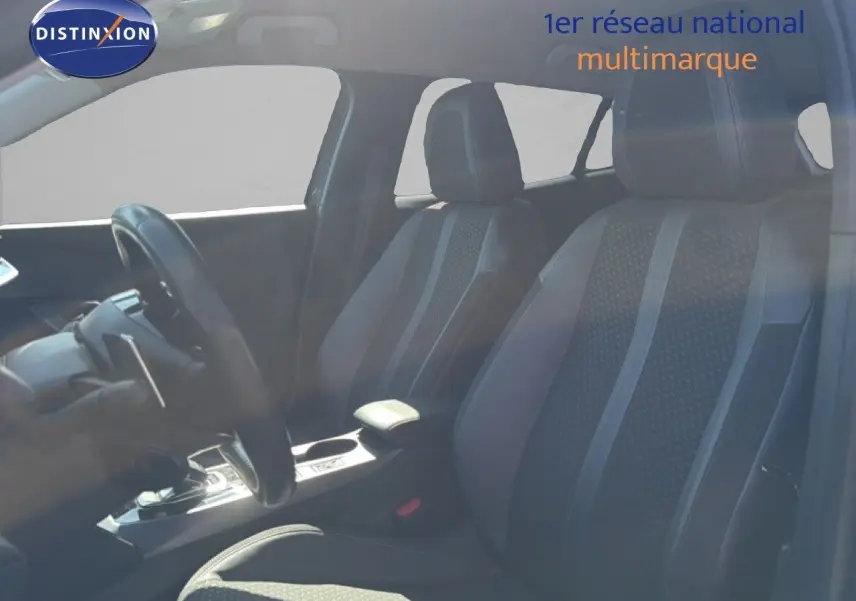 Vue intérieure de profil droit montrant les sièges avant en tissu noir et la console centrale d'une Peugeot 2008 gris platinium.