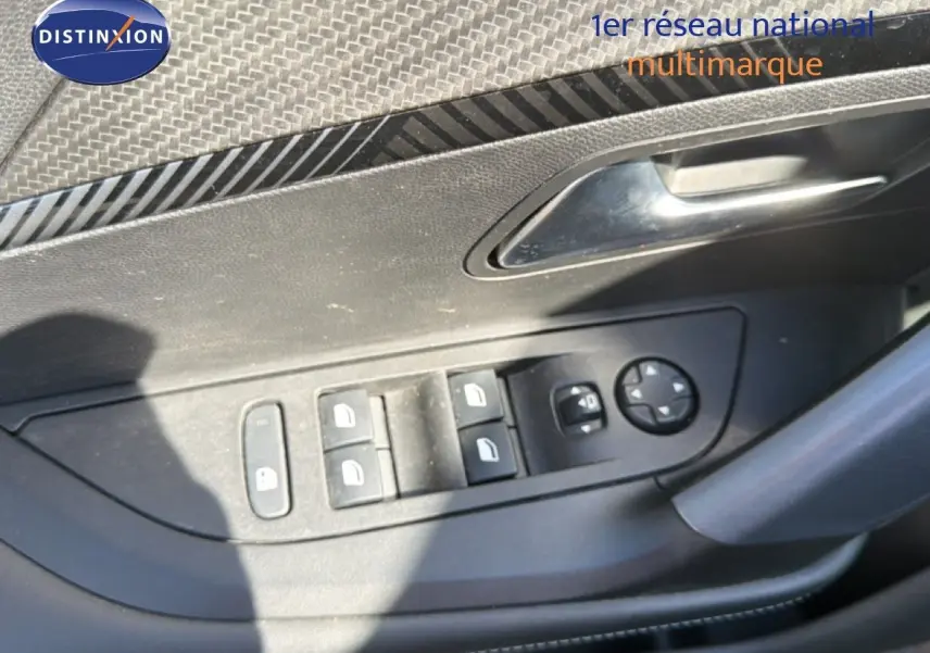 Détail des commandes des vitres et rétroviseurs sur la porte côté gauche d’un Peugeot 2008 gris platinium.