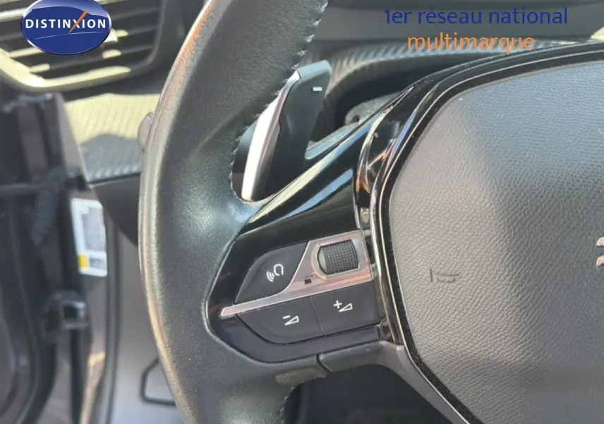 Gros plan sur le volant noir de la Peugeot 2008 1.2 PureTech 130 Allure, montrant les commandes audio et de volume.