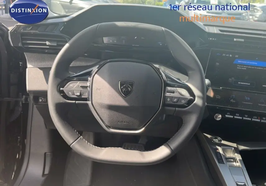 Vue intérieure centrée sur le volant noir de la Peugeot 308 Hybrid 145ch 2025 avec tableau de bord et écran tactile.