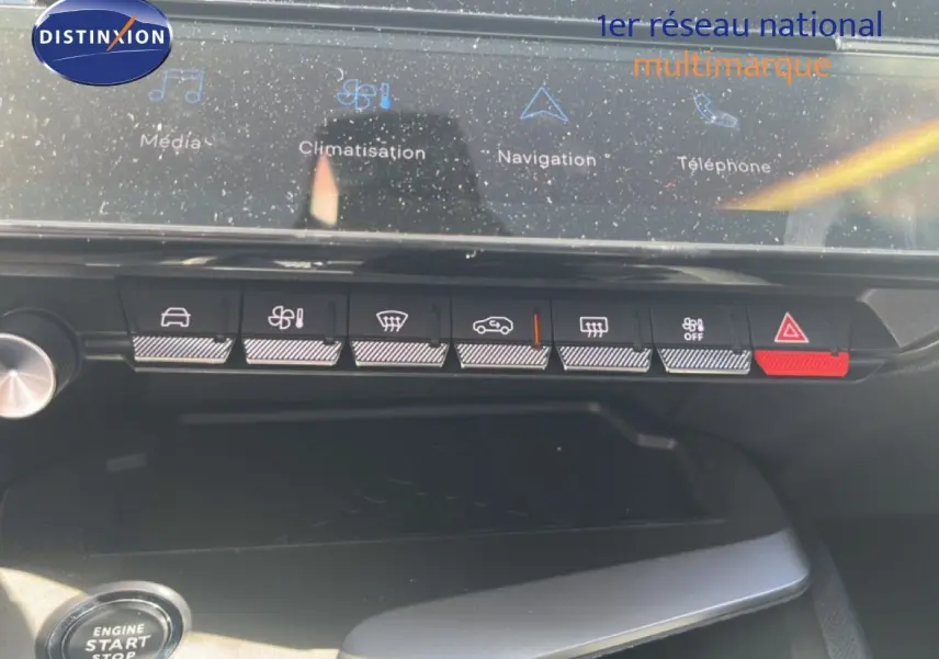 Vue rapprochée du tableau de bord de la Peugeot 308 Hybrid 2025, montrant les commandes tactiles et boutons de climatisation et sécurité.