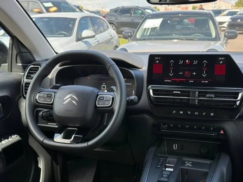 Vue intérieure centrée sur le volant et l’écran tactile du tableau de bord du Citroën C5 Aircross blanc Okénite.