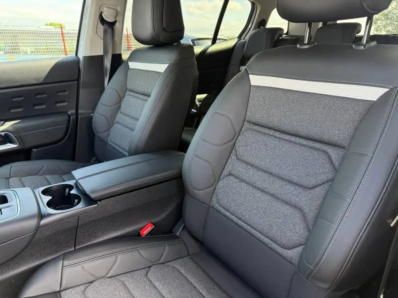Vue intérieure des sièges avant en tissu noir et cuir avec accoudoir central du Citroën C5 Aircross blanc Okénite.