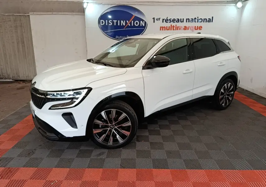 Renault Austral blanc en 3/4 avant droit, avec jantes noires et toit blanc dans un showroom intérieur.