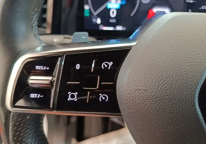 Gros plan sur les commandes multifonctions du volant cuir du Renault Austral blanc, avec affichage numérique en arrière-plan.