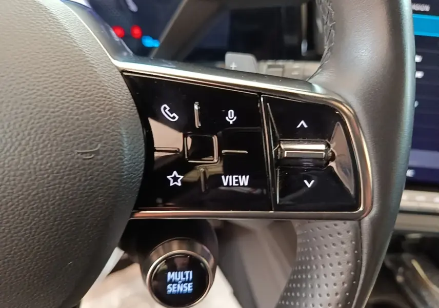 Gros plan sur le volant cuir du Renault Austral blanc 2023, avec commandes multifonctions et bouton Multi Sense éclairé.