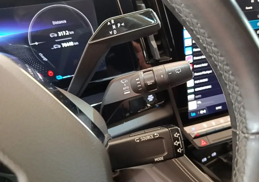 Gros plan intérieur sur les commandes au volant du Renault Austral blanc, avec écran tactile et affichage numérique.