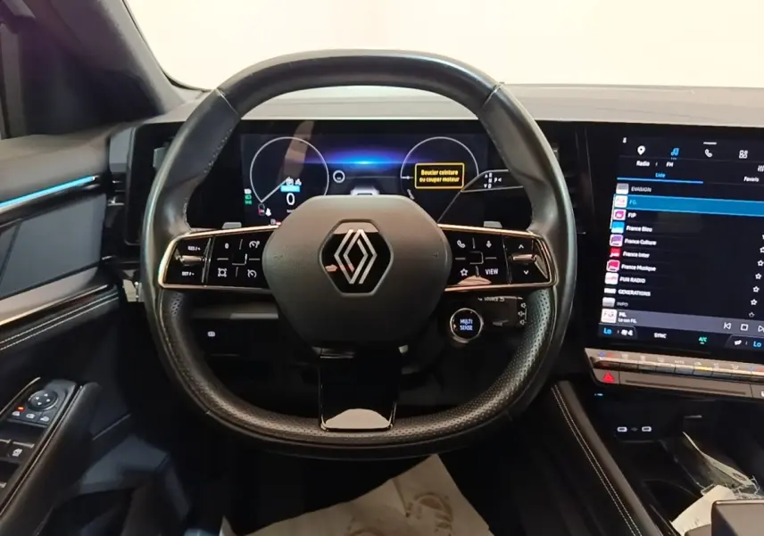 Vue centrée sur le volant cuir noir et le tableau de bord numérique du Renault Austral blanc, version hybride 2023.