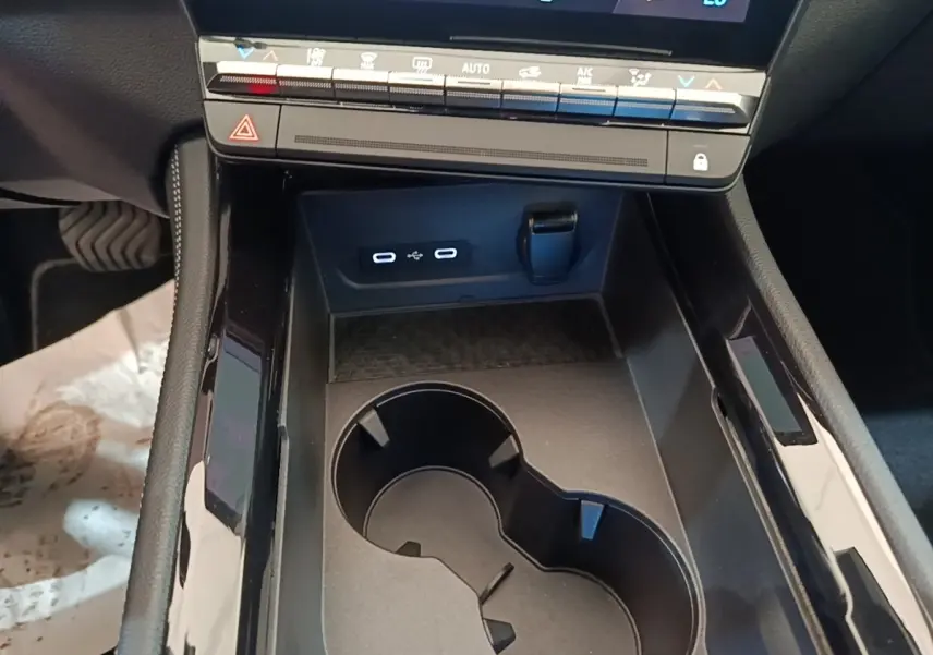 Gros plan sur la console centrale noire du Renault Austral blanc, avec porte-gobelets et ports USB-C visibles.