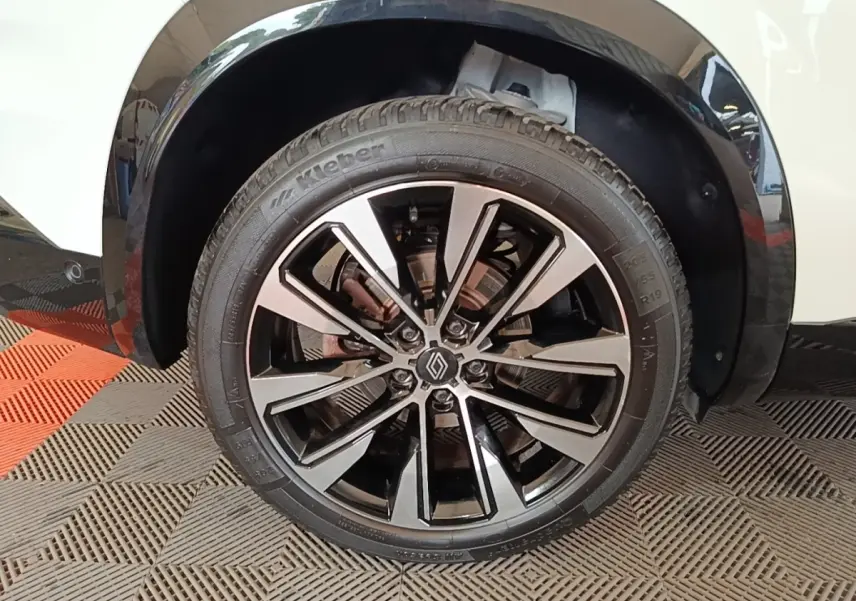 Gros plan sur la roue avant droite du Renault Austral blanc, mettant en valeur la jante alliage noire et argentée.