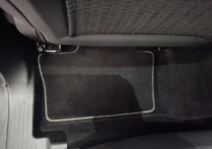 Détail du tapis de sol noir sous le siège arrière du Renault Austral blanc version Techno E-Tech Hybride 200.
