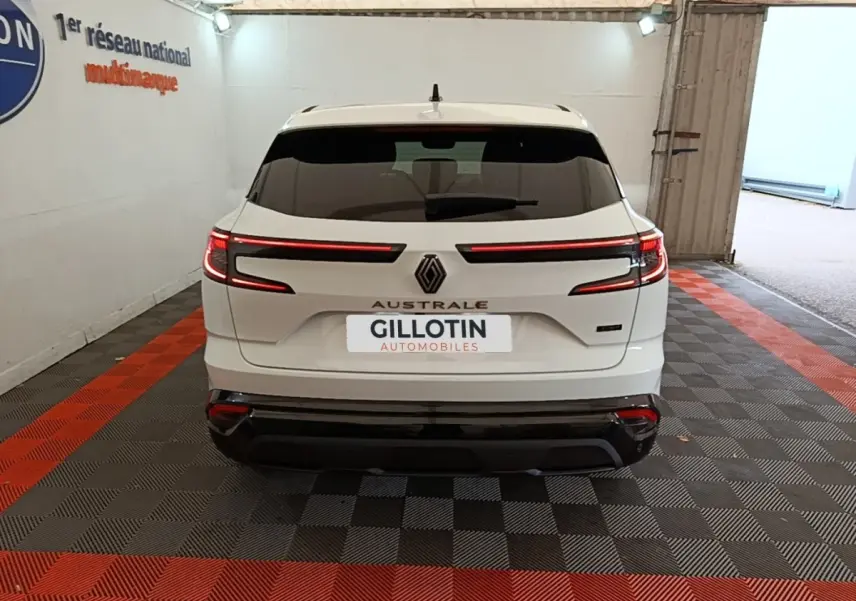 Vue arrière d'un Renault Austral blanc 2023 avec feux LED horizontaux et logo central dans un garage.