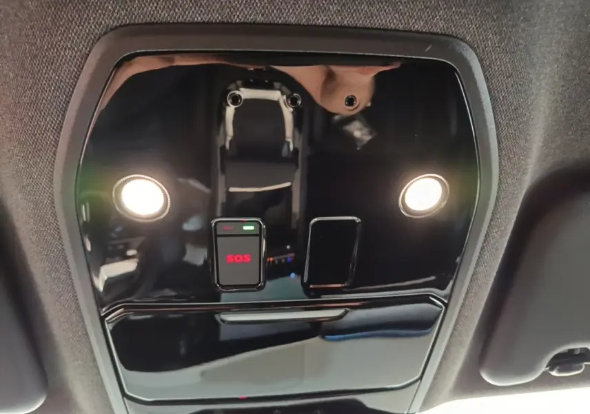 Vue intérieure en gros plan du plafonnier noir brillant avec bouton SOS éclairé et deux lampes de lecture allumées.